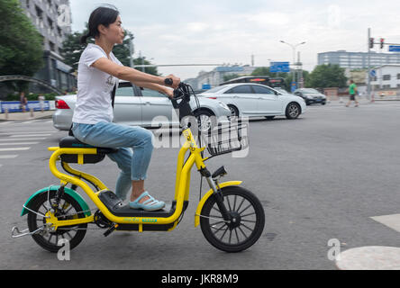 A lady rides shared motorbike on a street in Beijing, China. 24-Jul-2017 Stock Photo