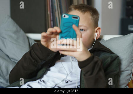 Boy listening music while using smart phone at home Stock Photo