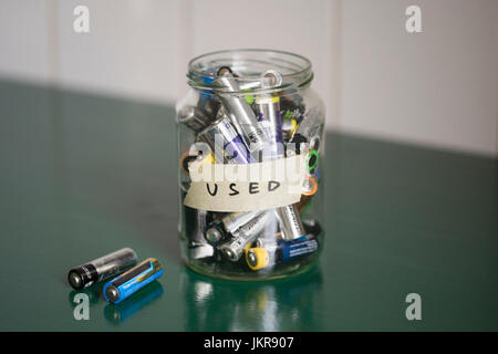 High angle view of batteries in glass jar with USED label on table Stock Photo