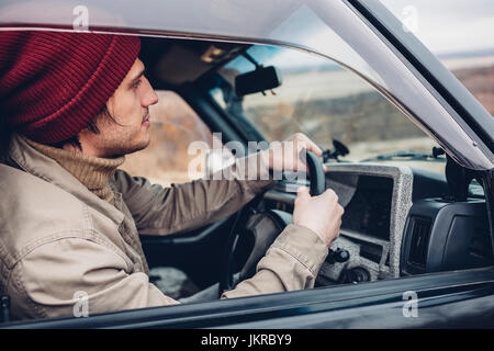 Side view of man wearing knit hat riding sport utility vehicle Stock Photo