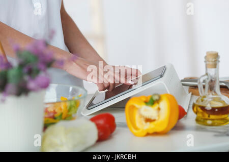 Cropped image of woman using digital tablet while preparing salad at kitchen counter Stock Photo