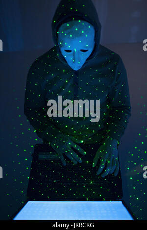 High angle view of green lights over computer hacker wearing mask using laptop Stock Photo