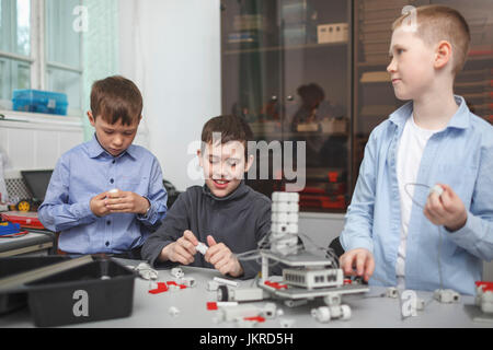 Smiling students working on machine part at table in classroom Stock Photo