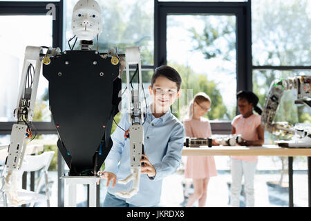 Dark-haired boy standing near a human robot Stock Photo