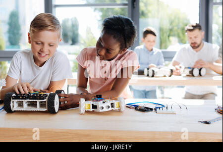 Girl examining the wheel of her friends robotic vehicle Stock Photo