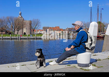 Woman with Miniature Schnauzer, black-silver, at harbour, Enkhuizen, Netherlands / Defence tower 'Dromedaris' Stock Photo