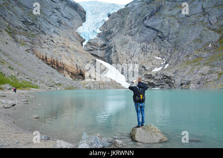 man taking picture of briksdal glacier, largest glacier in europe, olden norway Stock Photo