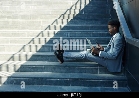 Young successful specialist with modern gadgets working outdoors Stock Photo