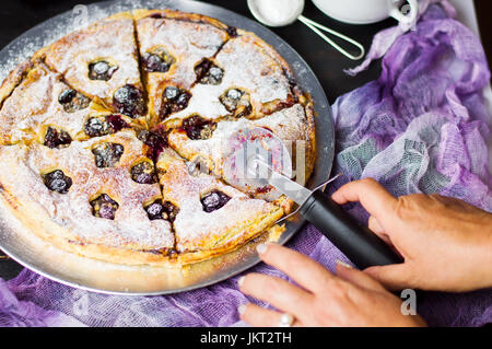 Female hand cutting sweet pie with a roller cutter Stock Photo