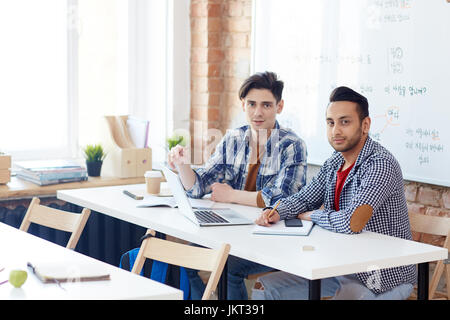 Busy college students or designers networking by desk Stock Photo