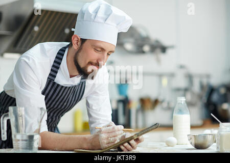 Young chef making notes in notepad Stock Photo