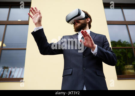 Mobile businessman with vr goggles in urban environment Stock Photo