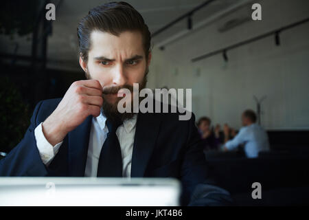 Pensive businessman reading online information Stock Photo