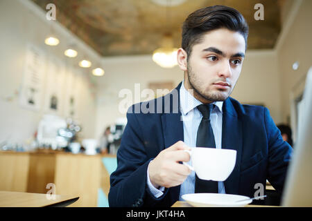 Young man in suit sitting in cafe and job hunting Stock Photo