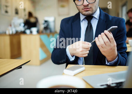 Mobile businessman charging his smartphone with battery Stock Photo