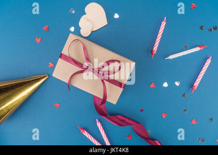 top view of gift box, birthday hat and candles isolated on blue, birthday party concept Stock Photo