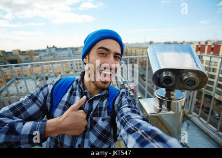 Portrait of happy young man showing thumbs up to camera taking selfie photo Stock Photo