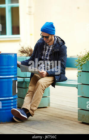 Portrait of modern young man  looking up directions in map tourist guide traveling alone in streets of old city Stock Photo