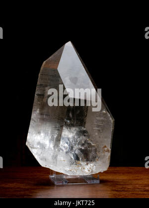 Clear Rock Crystal on a wooden table against a dark background Stock Photo