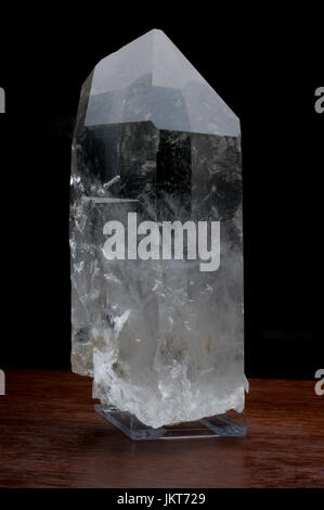 Clear Rock Crystal on a wooden table against a dark background Stock Photo