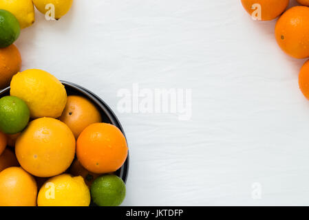 Bowl with different types of whole citruses: oranges, grapefruits, limes and lemons on white cloth background with copy space Stock Photo