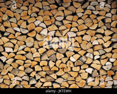 pattern of fully stacked neat woodpile with hewn ends of split logs in Cumbria, England, UK Stock Photo