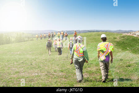 Group of workers in hardhats walking and inspecting grass field Stock Photo