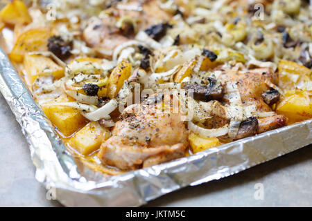 Oven roasted chicken thighs and yukon gold potatoes with leeks and herbs on a baking sheet lined with aluminum foil Stock Photo