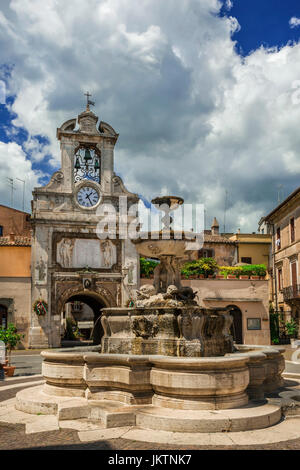 Sutri main square in the historic city center with fountain, old clock tower and clouds Stock Photo