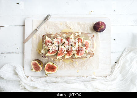 Loaf cake with figs, almond and white chocolate on wooden serving board Stock Photo