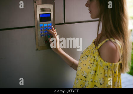 woman dials an apartment code on an electronic doorphone panel Stock Photo