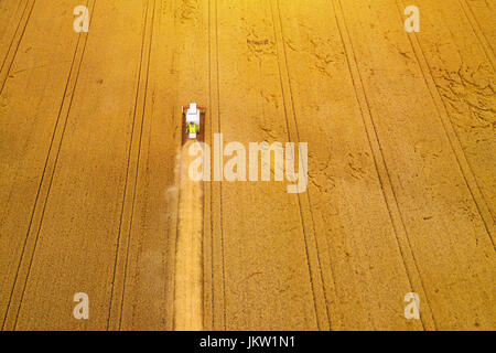 Aerial view of combine harvester agricultural machinery harvesting wheat crops in cultivated field