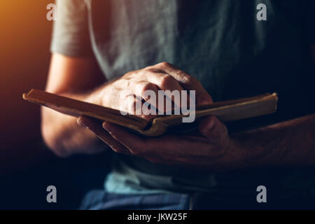 Reading an old book, close up of male hands flipping vintage weathered book pages Stock Photo