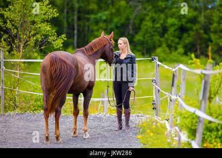 Young woman with her arabian horse standing at a riding course Stock Photo