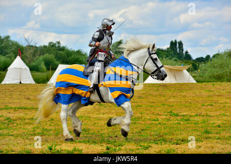 Medieval Knights in full plate armour with sward galloping on horseback Stock Photo
