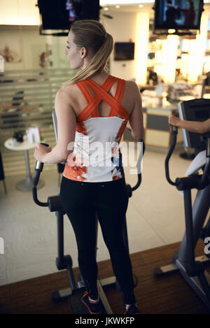 Rear view of young woman using anaerobic exercise machine in gym Stock Photo