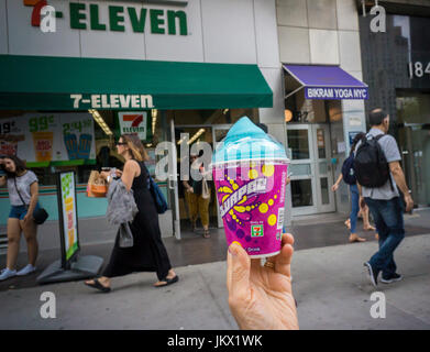 A Slurpee lover displays her free drink outside a 7-Eleven store in New York on Tuesday, July 11, 2017 (7-11, get it?), Free Slurpee Day! This year the chain is celebrating it's 90th birthday. The popular icy, slushy, syrupy drinks are available in regular and diet flavors, in combinations, and the stores have stocked up with extra barrels of syrup to meet the expected demand. According to the meticulous figures kept by 7-Eleven they sell an average of 14 million Slurpees a month and over 150 million Slurpees a year.  (© Richard B. Levine) Stock Photo