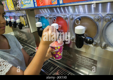 A worker fills a Slurpee in a 7-Eleven store in New York on Tuesday, July 11, 2017 (7-11, get it?), Free Slurpee Day! This year the chain is celebrating it's 90th birthday. The popular icy, slushy, syrupy drinks are available in regular and diet flavors, in combinations, and the stores have stocked up with extra barrels of syrup to meet the expected demand. According to the meticulous figures kept by 7-Eleven they sell an average of 14 million Slurpees a month and over 150 million Slurpees a year.  (© Richard B. Levine) Stock Photo