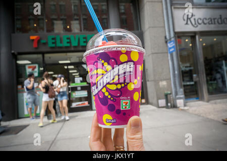 A Slurpee lover displays her free drink outside a 7-Eleven store in New York on Tuesday, July 11, 2017 (7-11, get it?), Free Slurpee Day! This year the chain is celebrating it's 90th birthday. The popular icy, slushy, syrupy drinks are available in regular and diet flavors, in combinations, and the stores have stocked up with extra barrels of syrup to meet the expected demand. According to the meticulous figures kept by 7-Eleven they sell an average of 14 million Slurpees a month and over 150 million Slurpees a year.  (© Richard B. Levine) Stock Photo