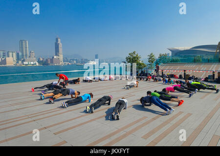 HONG KONG, CHINA - JANUARY 26, 2017: Crowd of people doing Tai Chi Exercising in the morning, with a downton of the city of Hong Kong as background. With a land of 1,104 km and population of 7 million, Hong Kong is one of most densely populated areas in the world Stock Photo