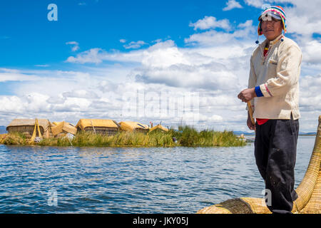 UROS ISLANDS, PERU - CIRCA APRIL 2014: Man from the Uros Islands in Lake Titicaca rowing in typical canoe made of totora reeds. Stock Photo