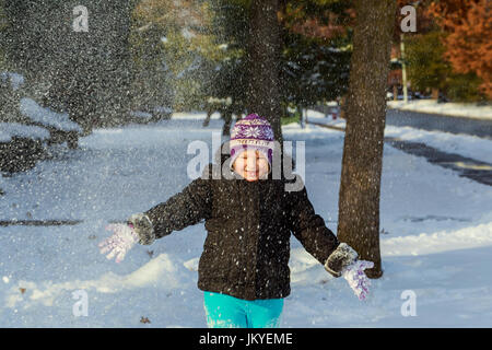Cute toddler girl in warm snowsuit playing with a snow. Little kid play having fun outdoors building snowman in the forest. Stock Photo