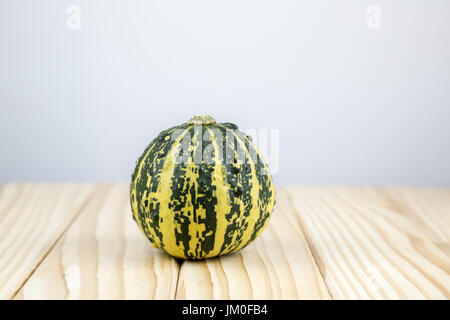 A decorative pumpkin (Italian Stripe) lying on wood with background for a text Stock Photo