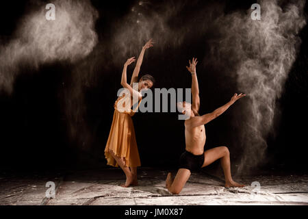 Beautiful couple ballet dancer with white powder explosion over black background Stock Photo