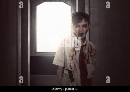 Scary asian zombie man in clothes standing on the dark room Stock Photo