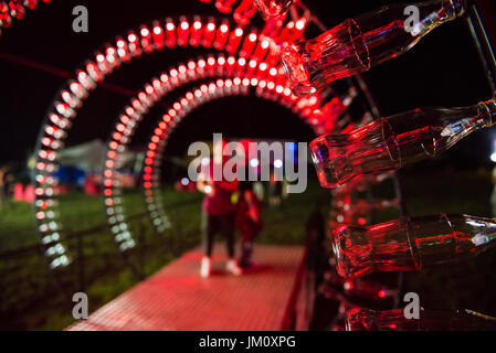BONTIDA, ROMANIA - JULY 13, 2017: Empty Coca Cola bottles are arranged in a shape of a tunnel and illuminated with red lights at Electric Castle festi Stock Photo