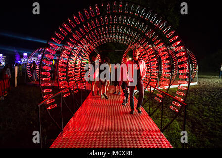 BONTIDA, ROMANIA - JULY 13, 2017: Empty Coca Cola bottles are arranged in a shape of a tunnel and illuminated with red lights at Electric Castle festi Stock Photo