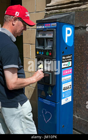 Man person buying ticket at on street car parking meter England UK United Kingdom GB Great Britain Stock Photo