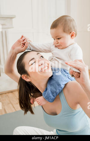 Portrait of young mother carrying her son piggyback at home Stock Photo