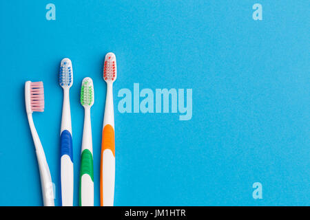 Multi-colored toothbrushes on blue background, space for text Stock Photo